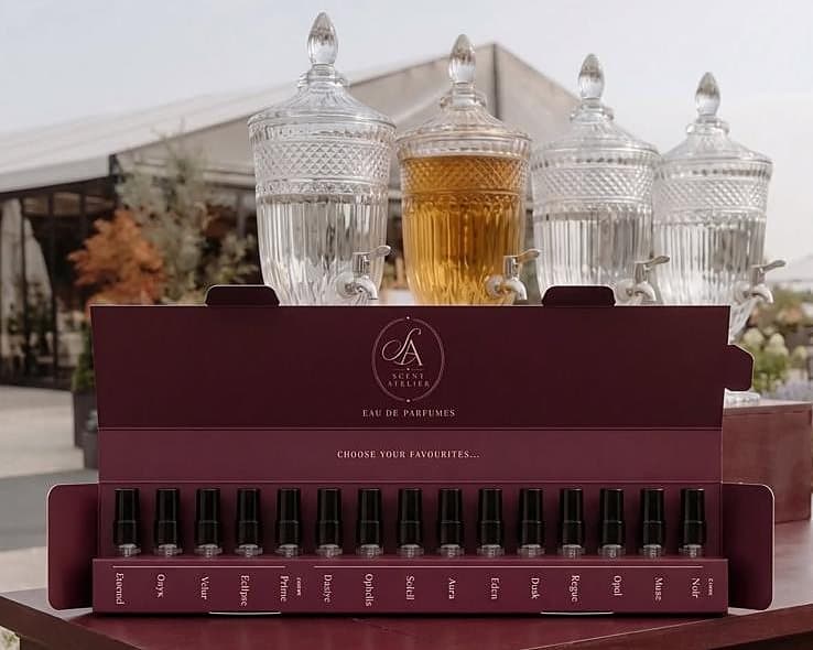 Otvoren Sample Box s petnaest testera ispred četiri kristalna dozatora parfemskog bara.