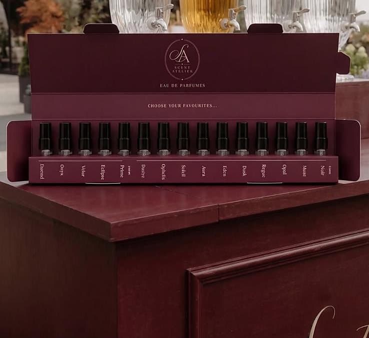 Otvoren Scent Atelier Sample Box na baru — petnaest testera parfema poredanih u oxblood kutiji.